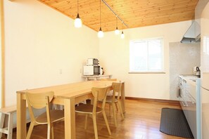 A dining area with a wooden table and chairs, a kitchen with a microwave, and a window with blinds. - Hakuba Shirousagi 3LDK 6person rental villa / Kitaazumi-gun Nagano (Kitaazumi-gun)