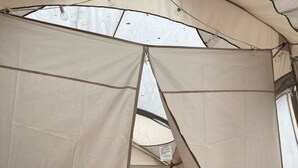 Una tenda amb un llit, almoadines i un estelatge a quadres.