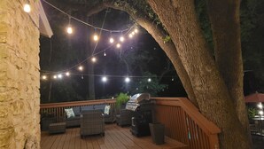 Una terrassa a l'aire lliure amb llums de garlandes, mobles de vímet i una barbacoa.