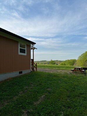 A wooden building with a porch and a picnic table in a grassy area. - Sleepy Bear #1. One Bedroom Cabin on the Blue Ridge Parkway in Floyd VA (Floyd)
