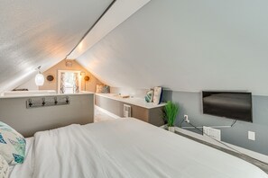 A modern bedroom with a large bed, a vanity with a mirror, a flat-screen TV mounted on the wall, and a small window. - Family Home w/ Private Pool: 24 Mi to Disney! (St. Cloud)