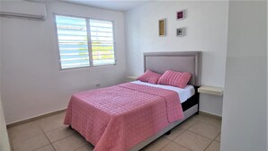 A bedroom with a bed, a window, and a wall-mounted shelf. - 3 Luquillo Beach 2/B Apartment with Swimming Pool (Luquillo)