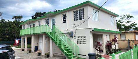 A two-story building with a green staircase and a white exterior.