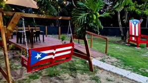 A wooden swing set with a flag design, a small table with chairs, and a bench. - 3 Luquillo Beach 2/B Apartment with Swimming Pool (Luquillo)