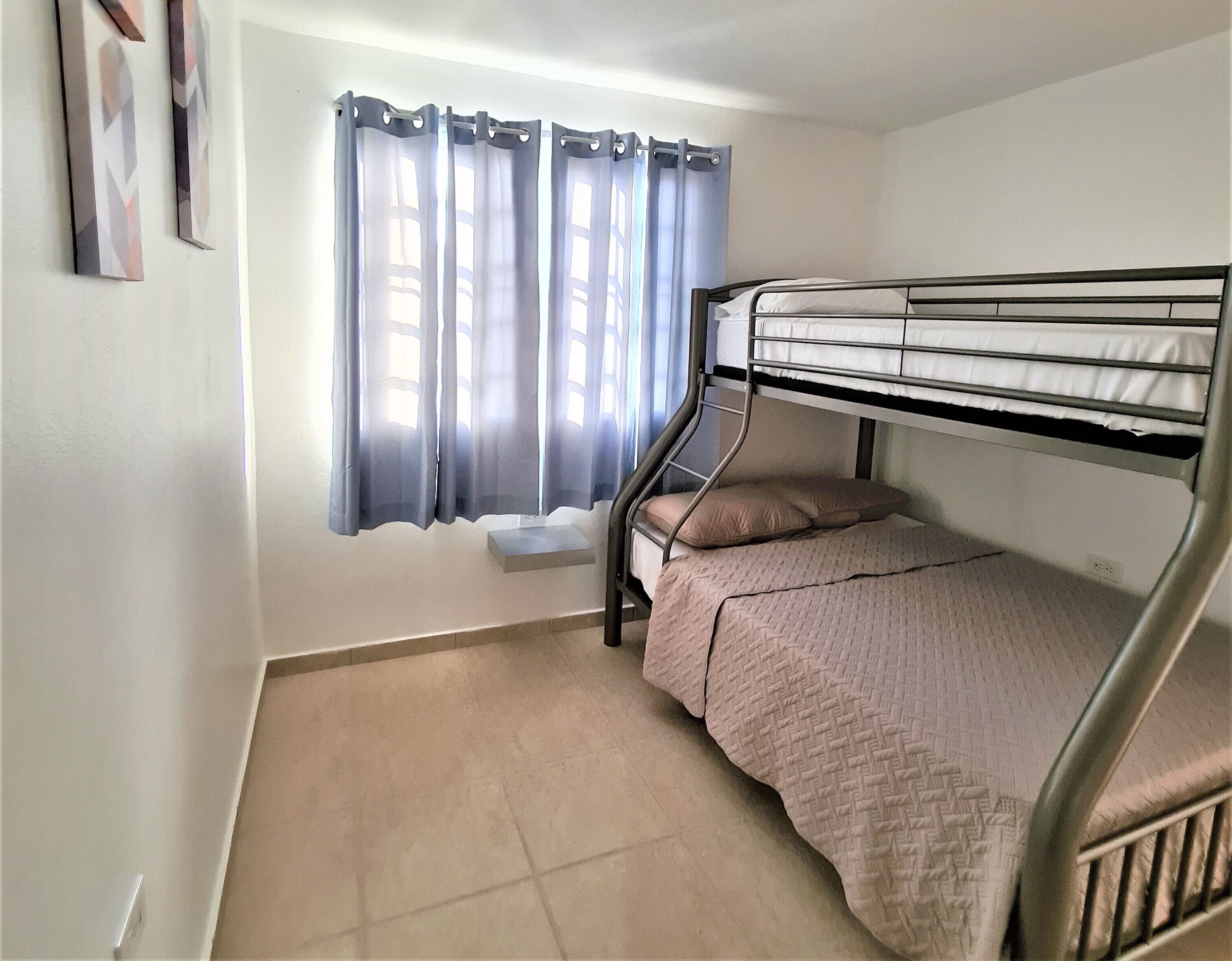 A bunk bed room with a window and curtains.