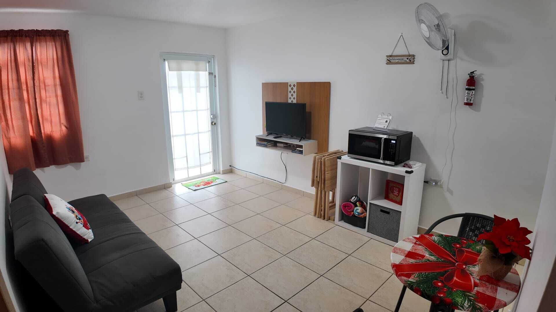 Un salon comprenant un canapé, un téléviseur, un four à micro-ondes et un ventilateur.