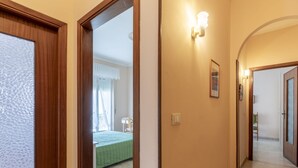 Un pasillo con una puerta de madera, un interruptor de luz y un cuadro en la pared.