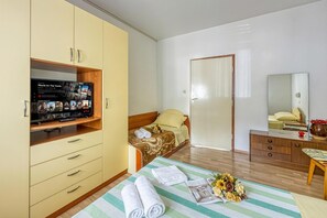 Une chambre dâhĂŽtel comprenant un lit, un tĂ©lĂ©viseur posĂ© sur un meuble, une armoire, une table de chevet et un miroir.