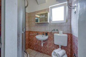 Ein Badezimmer mit Dusche, Waschbecken, Toilette und Spiegel.