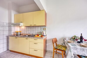 A compact kitchen with a sink, stove, and a dining area with a table set for two. - Seaside Apt Basic 2 w/ Terrace, Vir, Croatia (Vir)