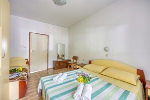Quarto de hotel com cama, escrivaninha, cadeira e guarda-roupa.