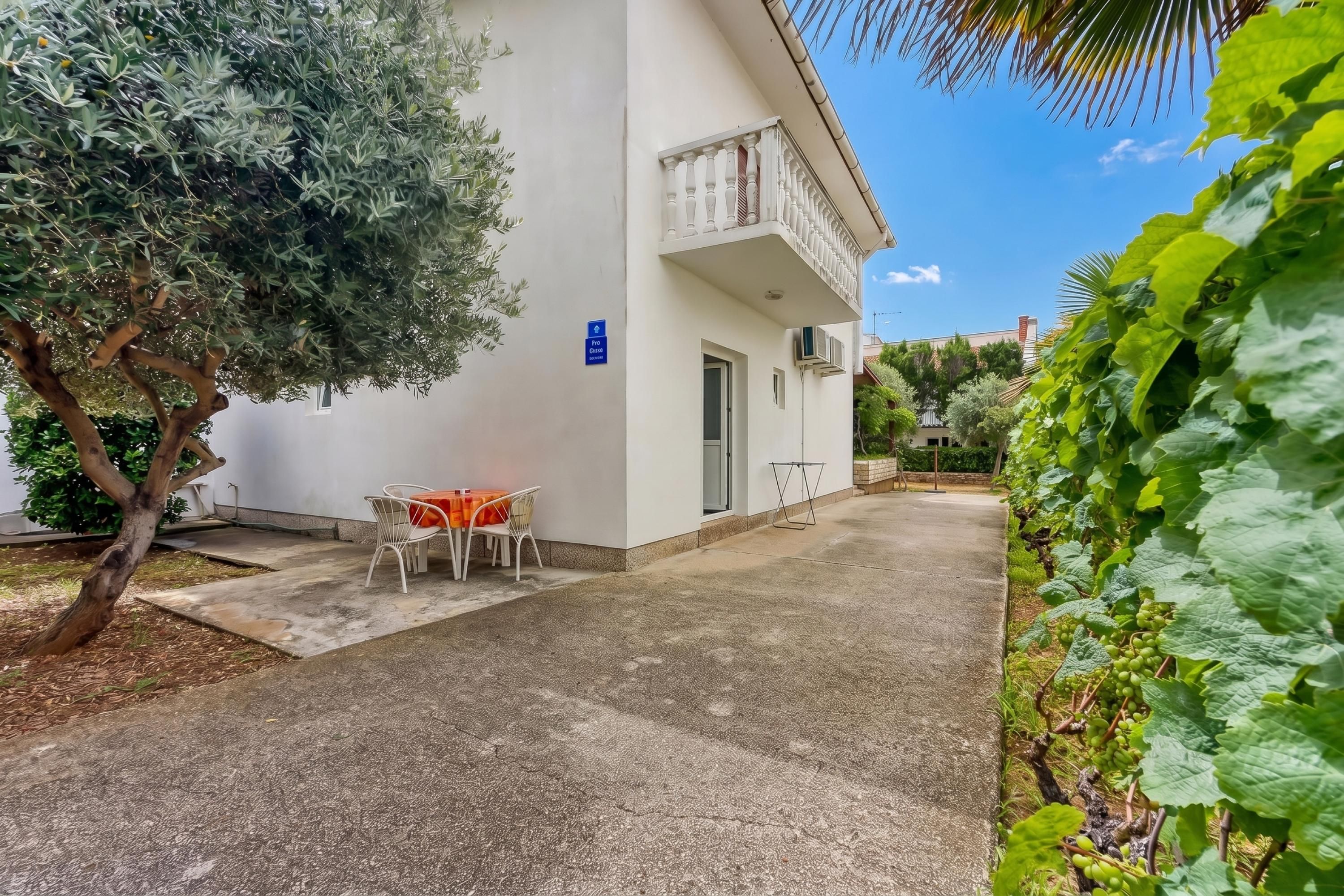 Ein Gebäude mit einem Balkon, einem Tisch mit Stühlen und einem Gartenbereich mit Pflanzen.