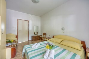 Ein Hotelzimmer mit Bett, Schreibtisch, Stuhl, Kleiderschrank und einer Tür.
