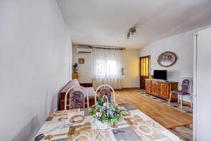 A living room with a sofa, two chairs, a television, a cabinet, and a decorative table with a floral centerpiece.