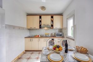A modern kitchen with white cabinets, a microwave, and a dining area set for a meal. - Seaside Apt Basic 1 w/ Balcony, Vir, Croatia (Vir)