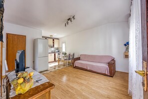 A compact living space with a kitchenette, a dining area, and a seating area with a sofa.