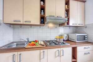 A kitchen with a stove, microwave, and a cutting board with vegetables.