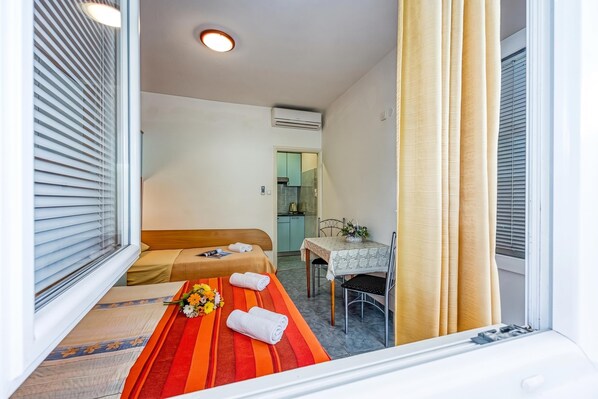 A hotel room with a bed, a table with a tablecloth, a chair, and a window with blinds.