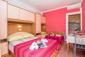 A hotel room with two beds, a kitchenette, and a dining area.