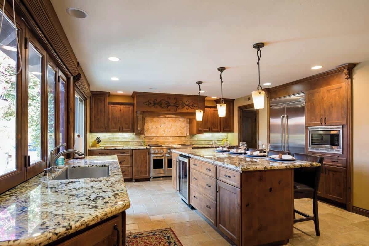 A spacious kitchen with granite countertops, stainless steel appliances, and wooden cabinetry.