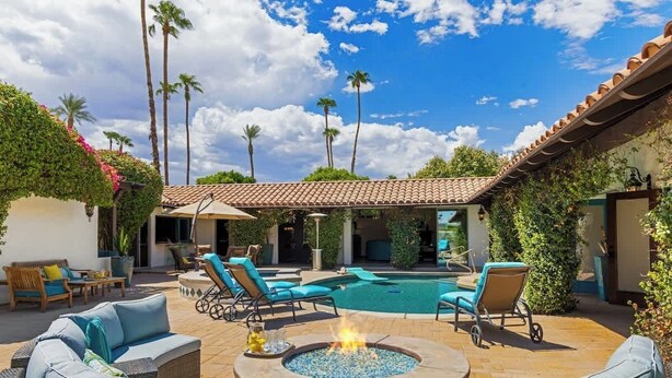 A poolside area with lounge chairs, a fire pit, and a swimming pool.
