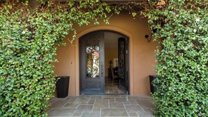 A building entrance with a black door, stone steps, and green foliage.