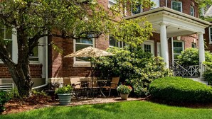 Un bâtiment en briques doté d’un patio couvert, d’un espace extérieur aménagé pour s’asseoir et d’un jardin bien entretenu.
