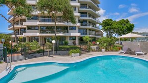 Ein modernes, mehrstöckiges Hotel mit Schwimmbad, Außenbereich und üppiger Bepflanzung.