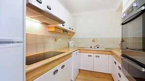 Eine kleine Küche mit weißen Schränken, einer schwarzen Arbeitsplatte und einem eingebauten Backofen.