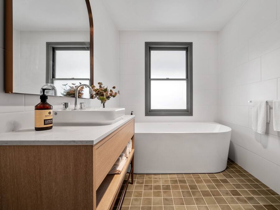 Une salle de bain moderne avec une baignoire sur pieds, un grand miroir et une fenêtre.
