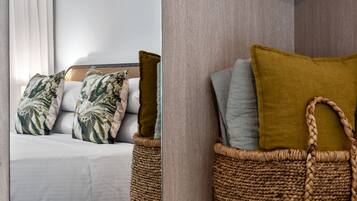 Una cama bien hecha con almohadas estampadas y una cesta tejida a su lado.