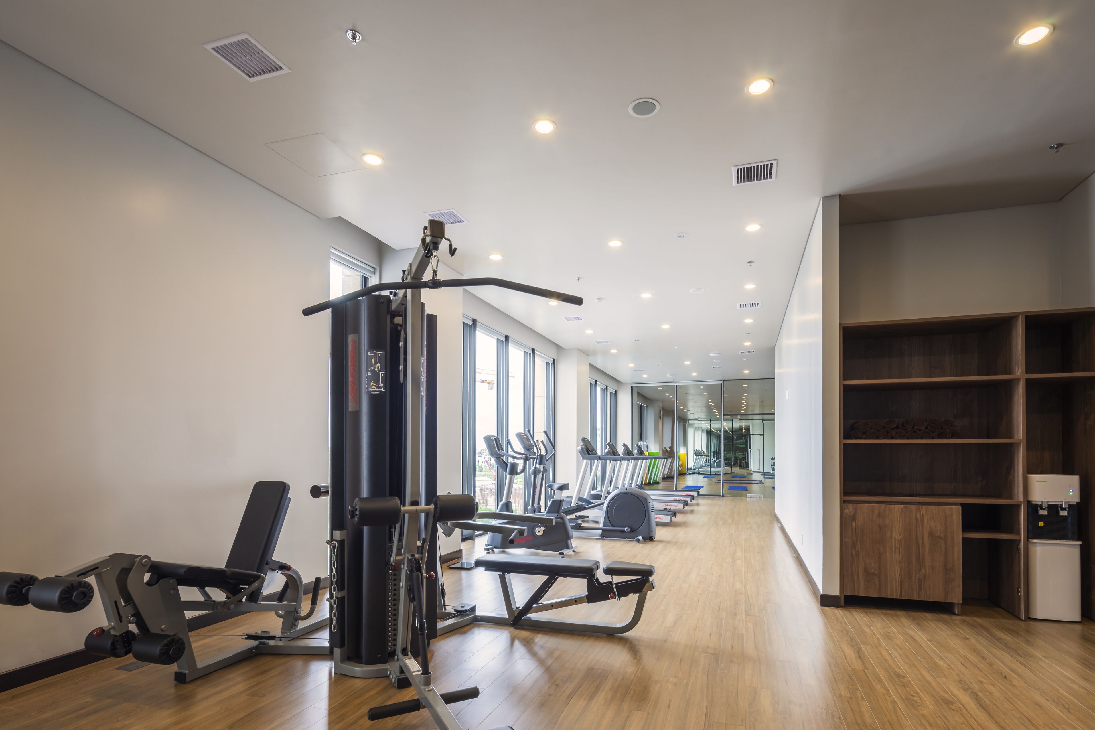 A gym with cardio machines, weightlifting equipment, and a water dispenser.