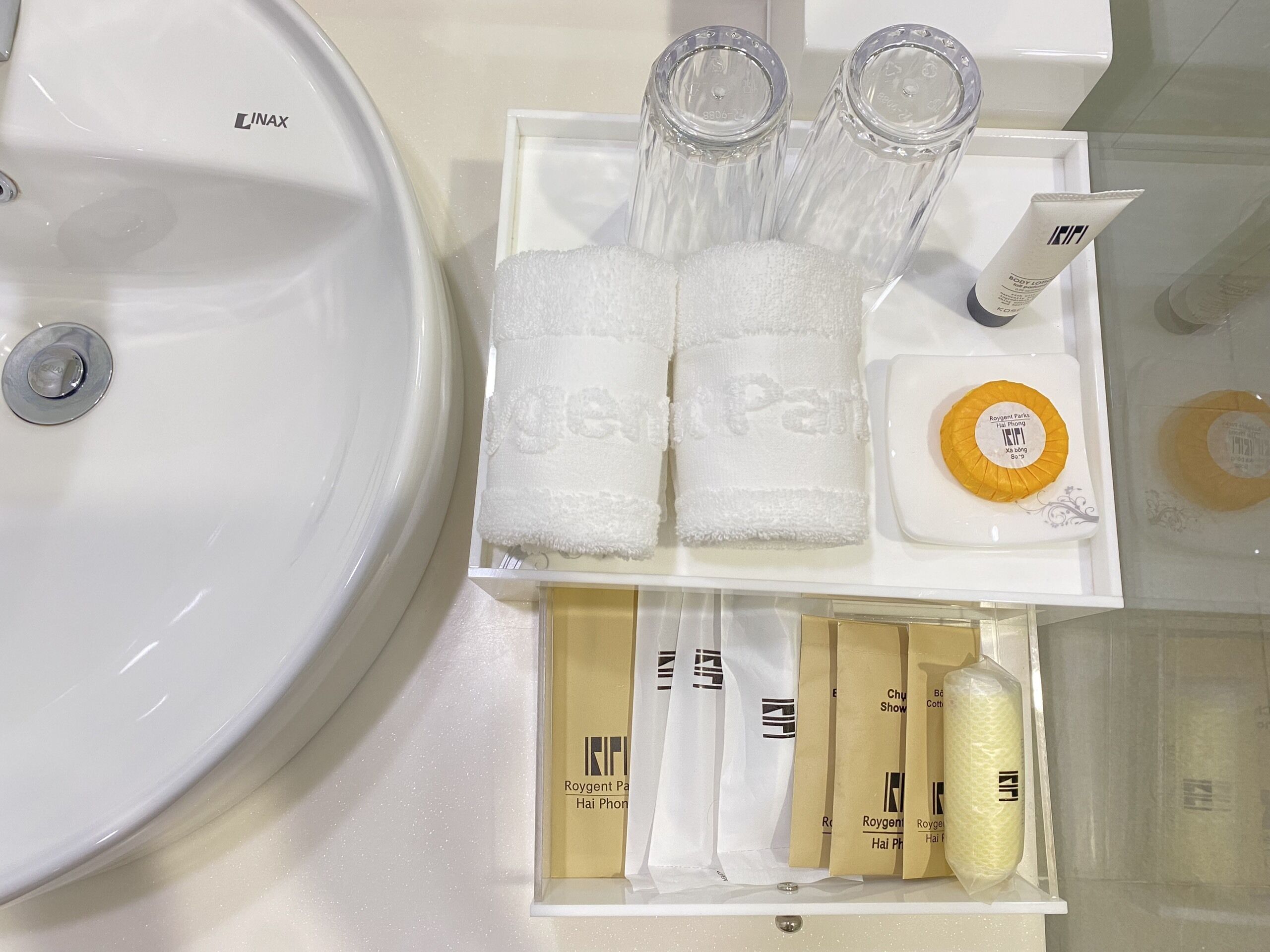 Un lavamanos de baño con un lavabo blanco y una bandeja blanca con artículos de aseo, incluyendo un cepillo de dientes, pasta de dientes y una toalla.