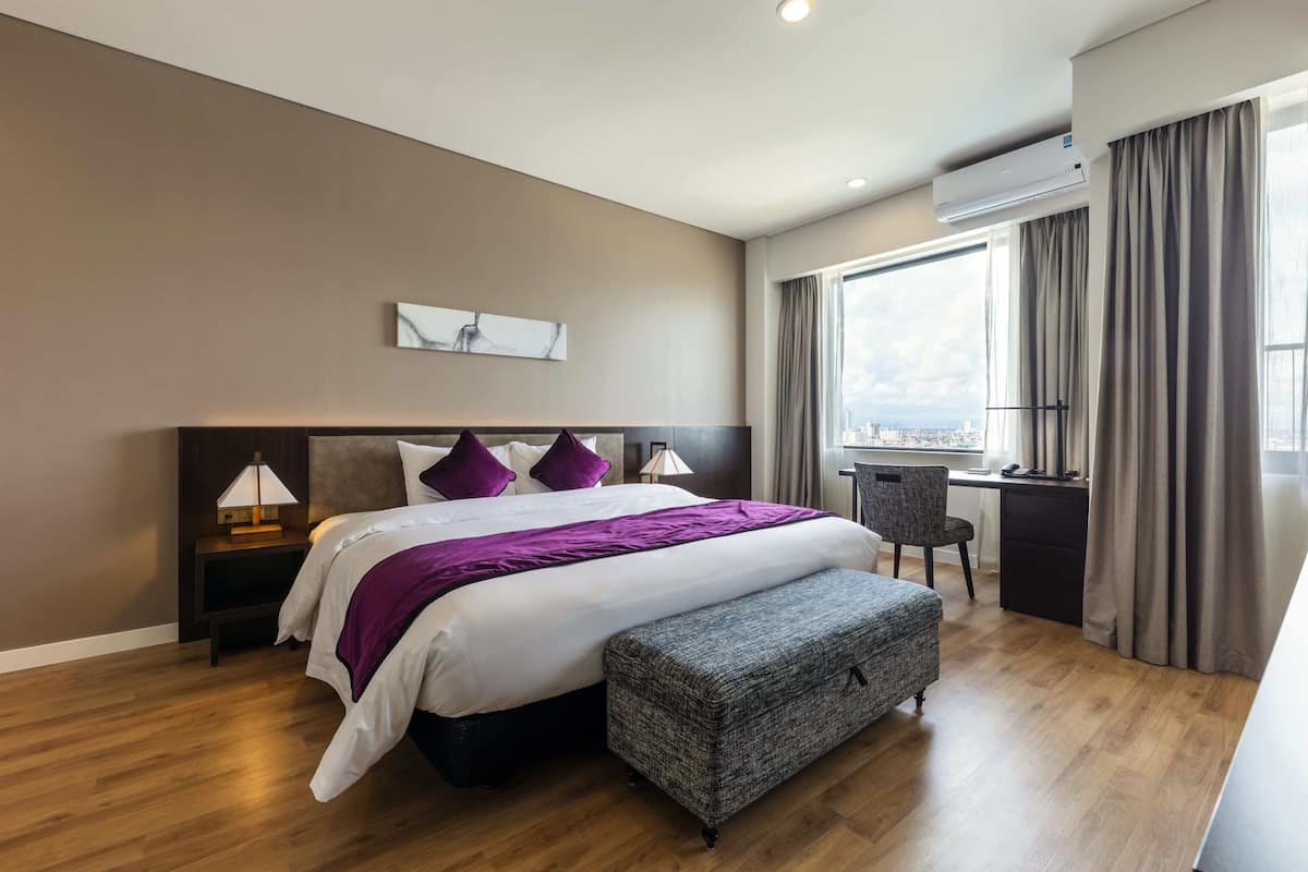 Une chambre d’hôtel moderne avec un grand lit, un bureau et une vue sur la ville.