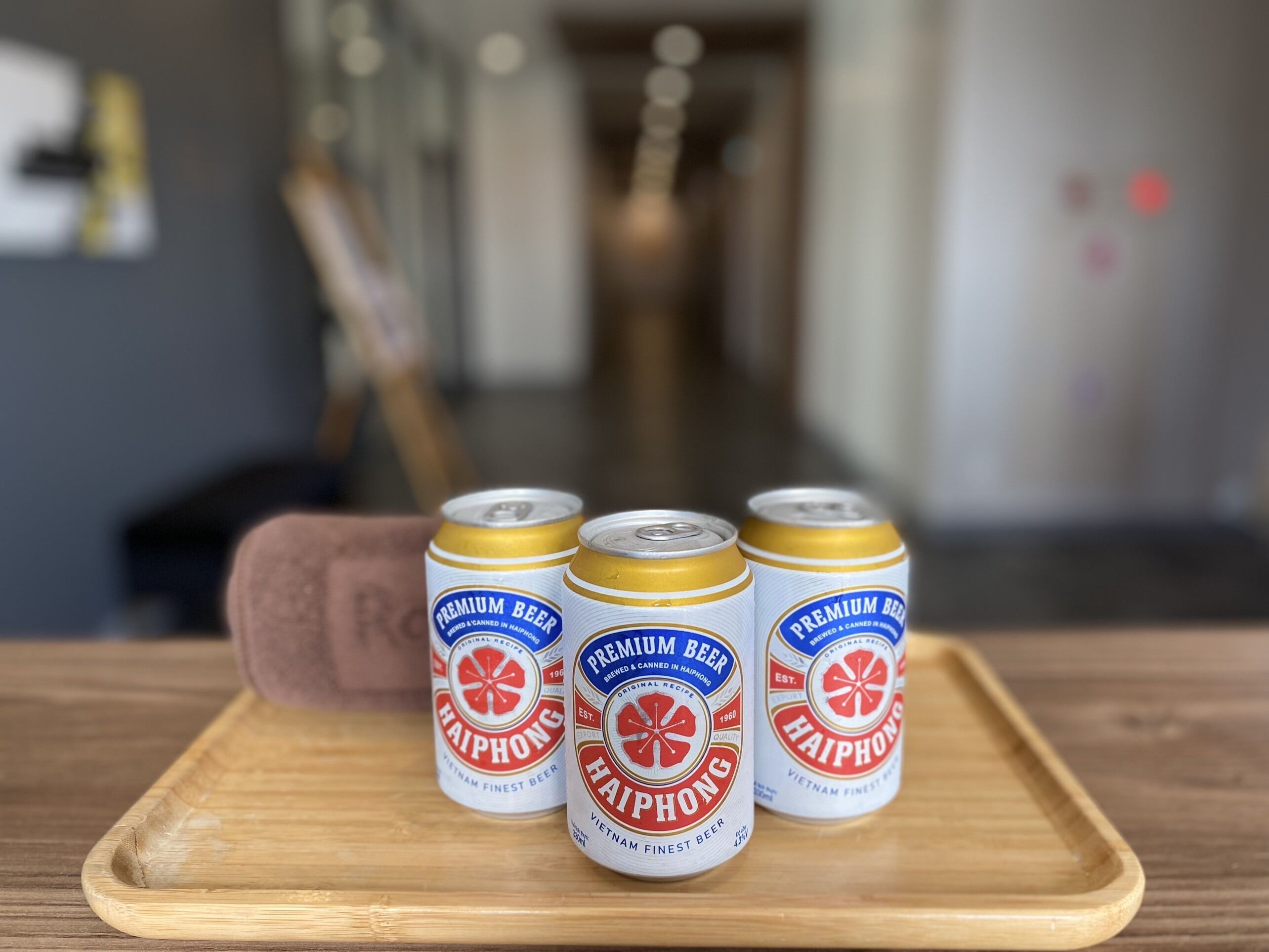 Three cans of Haiphong beer on a wooden tray.