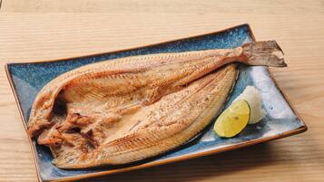 A fish on a ceramic plate with a slice of lime.