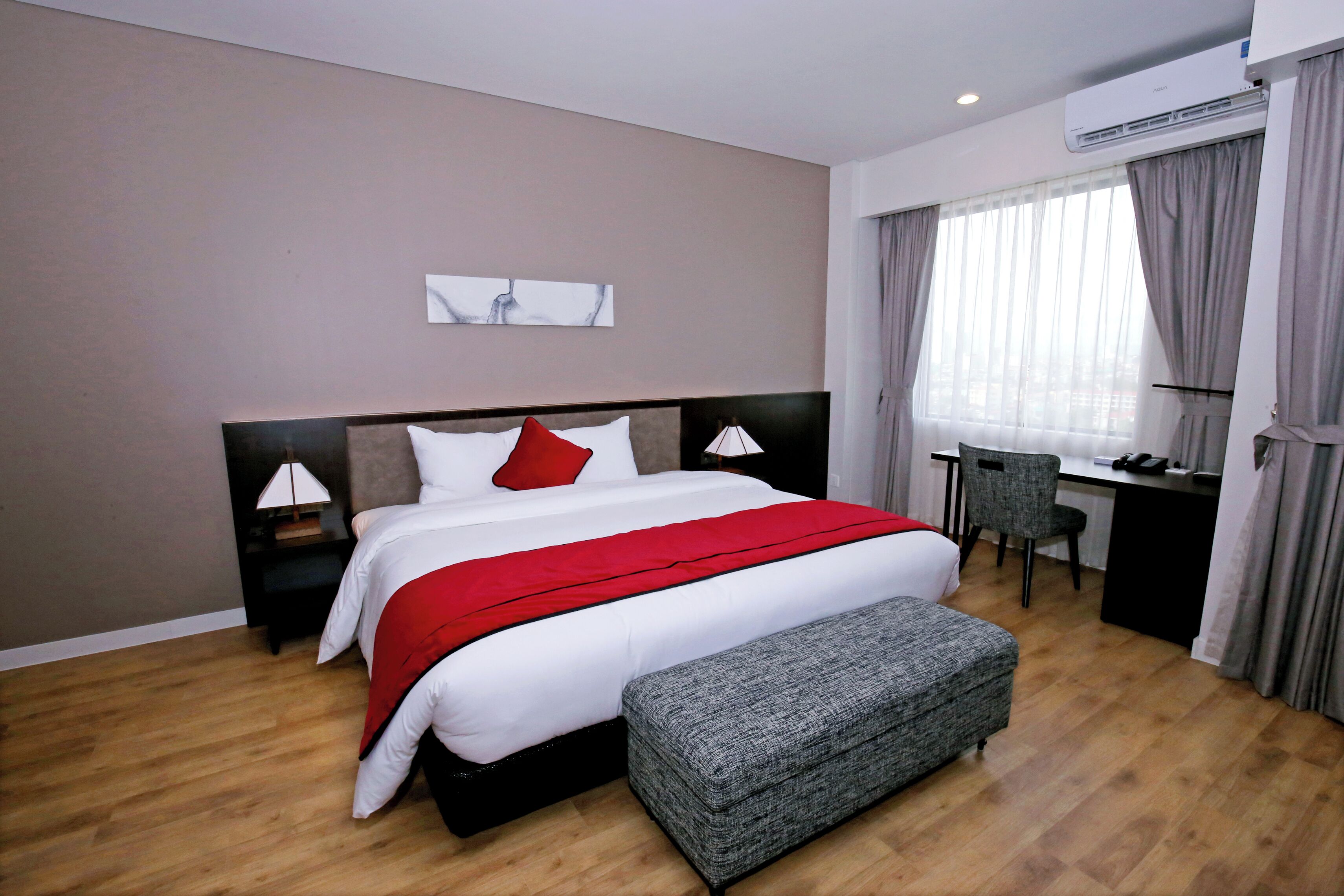 A modern hotel room with a large bed, a desk, and a chair.