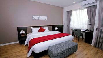 A modern hotel room with a large bed, a desk, and a chair.