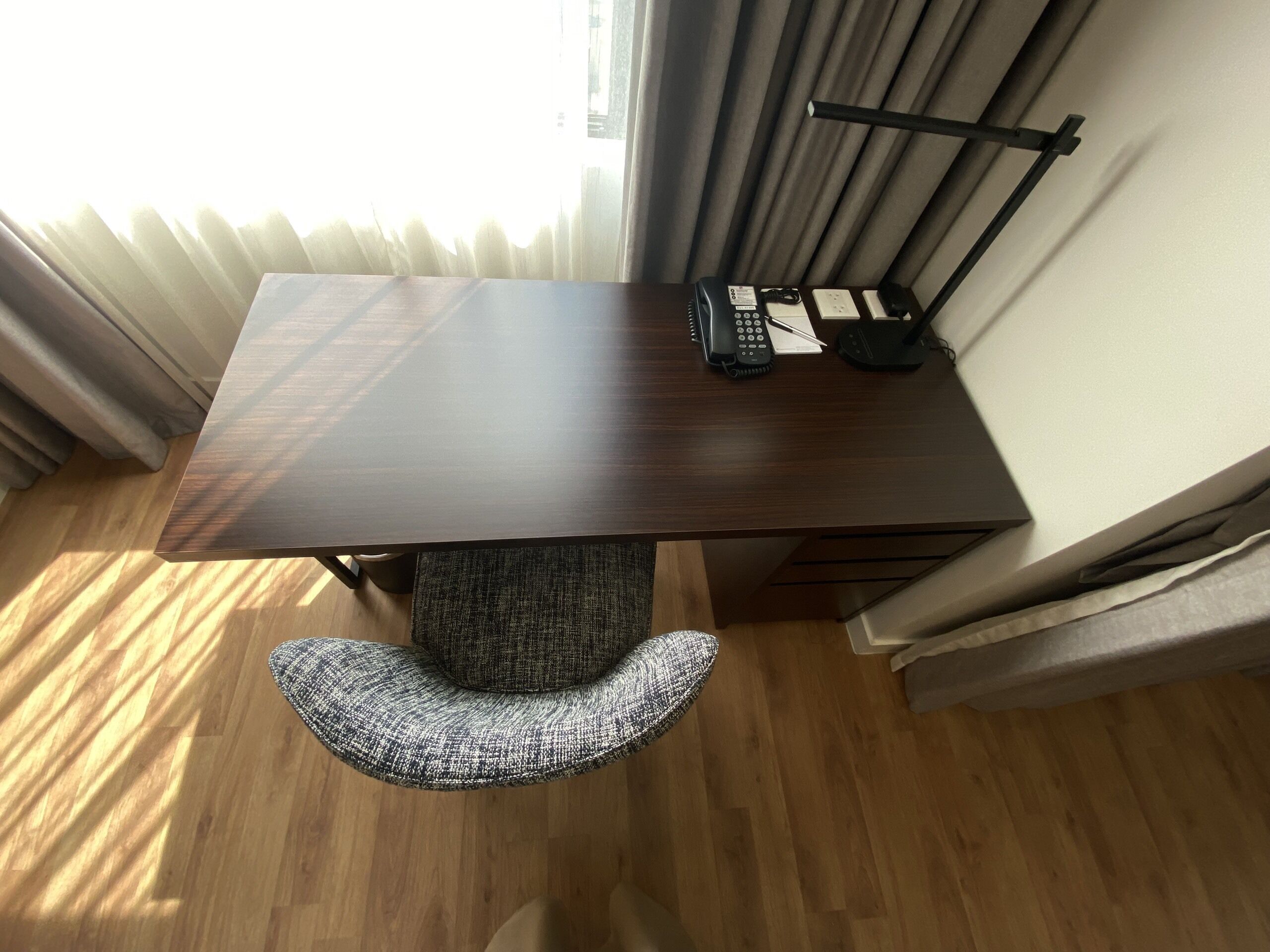 A modern dining table with a dark wood finish, a black telephone, and a notepad on it.