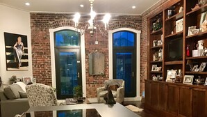 Un salon moderne avec une grande table noire, un vase décoratif en argent, un lustre et un mur en briques.