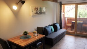 Et hyggeligt værelse med et træspisebord, en sofa og en skydedør til et udendørs område.