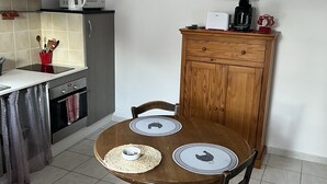Un comedor con una mesa de madera dispuesta para cuatro, una cocina al fondo y un armario decorado con un bigote.