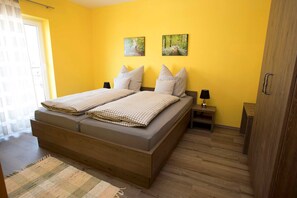 A bedroom with a wooden bed, two bedside tables, a nightstand, and a wardrobe.