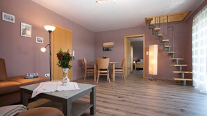 Una sala de estar moderna con suelo de madera, un sofá, una mesita de centro y una escalera que sube a otra habitación.