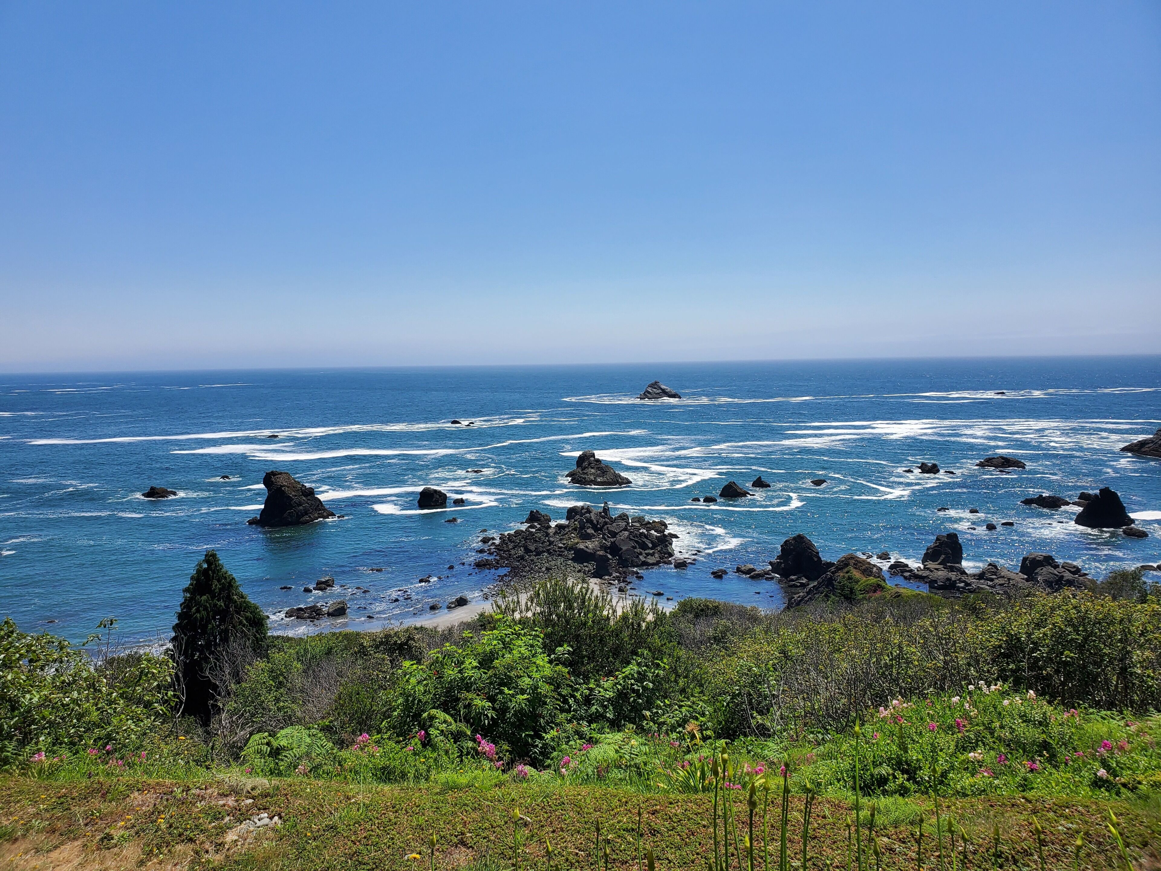 A coastal landscape with rocky outcrops and a clear view of the ocean.