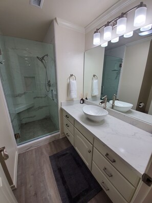 A modern bathroom with a glass-enclosed shower, a large mirror, a white sink, and a marble countertop. - "By The Sea" Oceanfront Updated Rainbow Rock Condo, Spectacular Views, 1st Floor (Brookings, OR 97415)