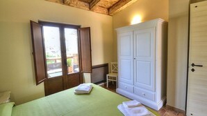 A bedroom with a bed, a wardrobe, a chair, and a window.