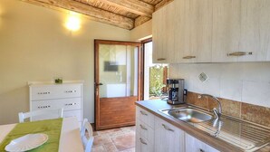 A kitchen with wooden cabinets, a sink, and a dining area with a table and chairs.