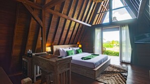 A high-ceilinged room with a wooden ceiling, a bed with green bedding, a wooden desk, and a view of greenery outside. - Alam Kawi Ubud Resort & Spa (Ubud)