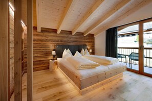 A wooden-paneled bedroom with a bed, bedside tables, and a view through a glass door.
